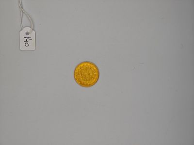 a gold coin sitting on a white surface next to a price tag