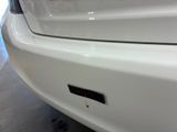 the front bumper of a white car with a sticker on it
