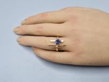 an image of a woman ' s hand with a gold ring and a sapphire stone