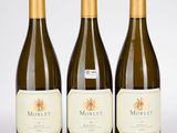 trois bouteilles de vin sont alignées sur une surface blanche