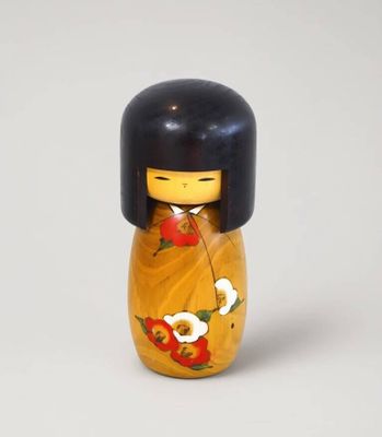 une petite poupée en bois aux cheveux noirs, vêtue d'un kimono jaune