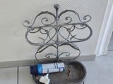 une brosse à dents et du dentifrice dans un porte-brosse en métal posé par terre