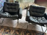 pair of black leather lounge chairs on a rug in a living room