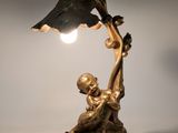 bronze statue of a boy holding a lamp with a bird on it ' s arm