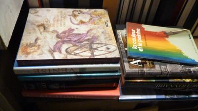 une pile de livres posée sur une table à côté d'une chaise