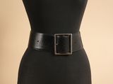 une femme vêtue d'une robe noire et d'une ceinture noire à boucle argentée
