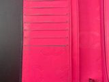 pink leather wallet with zippers open on a black surface