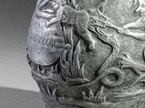 a silver vase with a picture of a man and a dog on it