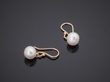a pair of pearl earrings on a black surface