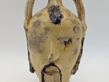 a yellow vase with a face on it on a white surface