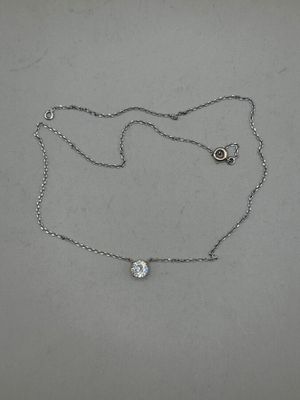 silver chain with a diamond pendant on it on a white surface