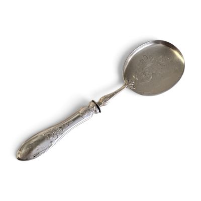 une cuillère en argent avec un manche en métal posée sur une surface blanche