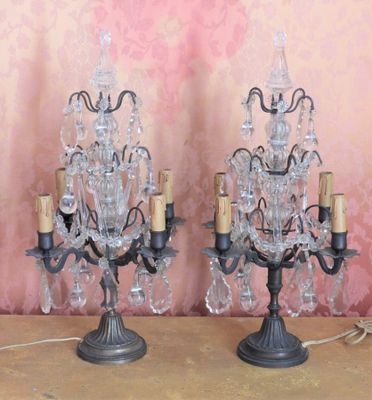 two crystal chandeliers on a table with a pink wall in the background