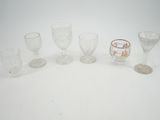 Plusieurs verres à pied et tasses sont alignés sur une surface blanche