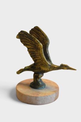 bronze sculpture of a bird on a wooden base on a white background