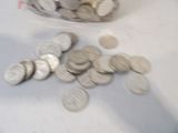 a jar full of coins sitting on a table next to a pile of coins