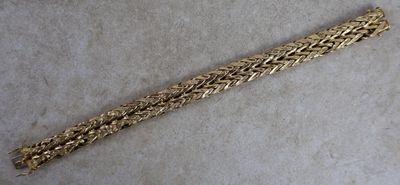 gros plan d'un bracelet en or sur une surface blanche