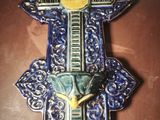 a blue and yellow wall hanging with a cross on it