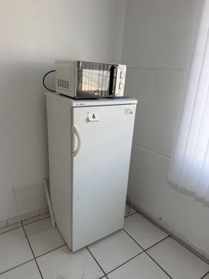 un petit réfrigérateur surmonté d'un micro-ondes