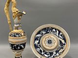 deux vases et une assiette posés sur une table sur laquelle se trouve un oiseau