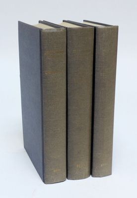 trois livres sont empilés sur une surface blanche