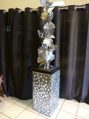 a statue of a woman sitting on a chair in front of a curtain