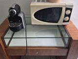 a microwave on a glass table with a coffee maker on it