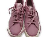 des baskets violettes avec des lacets sur le dessus, posées sur une surface blanche
