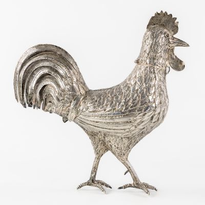 un coq argenté posé sur une surface blanche