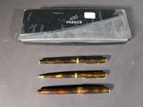 two pens and a box on a table next to each other
