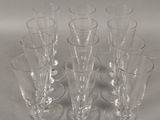 six verres à vin transparents sont alignés sur une surface blanche