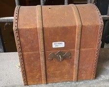 une petite valise marron posée par terre