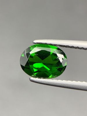 a close up of a green tourmaline gems being held by a pair of pliers