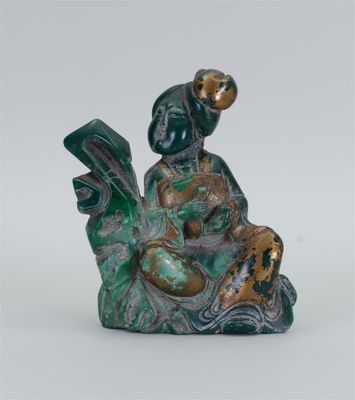 une image représentant une figurine d'une femme assise sur un rocher, en train de lire un livre