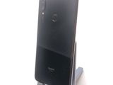 the back view of a black phone on a stand on a white surface