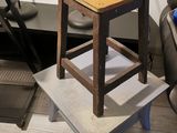 a small stool with a wooden seat next to a lamp