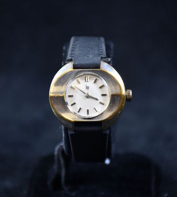 gros plan d'une montre en or sur une surface noire