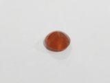 a close up of a red stone on a white surface