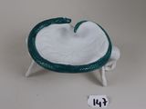 a small white bowl with a green handle on a stand