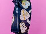 une femme portant un haut noir et une jupe bleue, avec un foulard Chanel