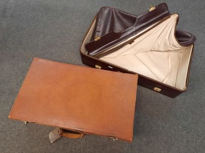 une valise marron posée par terre à côté d'une autre valise marron
