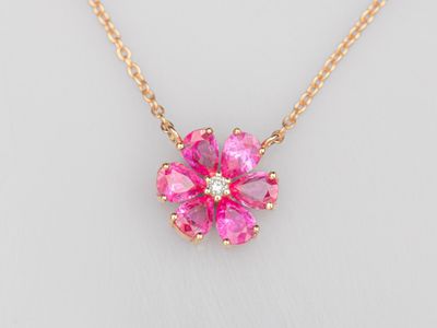 un collier avec une fleur rose sur une chaîne en or