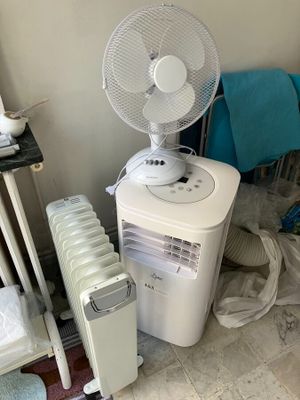 un ventilateur blanc posé sur une table à côté d'un radiateur