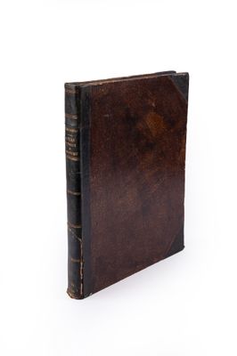 an old book with a brown cover sitting on top of a white surface