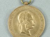 gold medal with a ribbon around the neck of a man