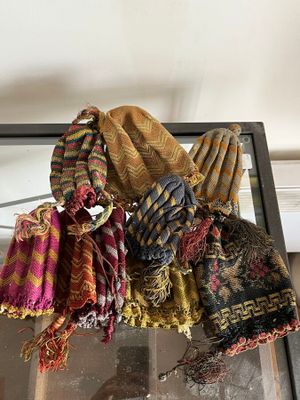 de nombreuses écharpes et bonnets posés sur une table en verre