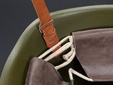 a green bucket with a brown handle and a pair of shoes in it