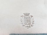 someone is holding a silver plate with a crest on it