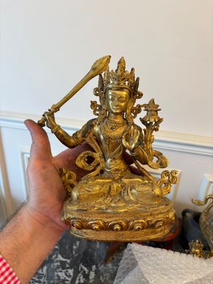 une personne tenant une statue en or dans la main