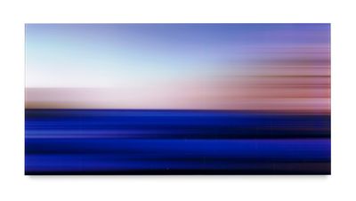 a blurry photo of a blue ocean with a pink sky in the background